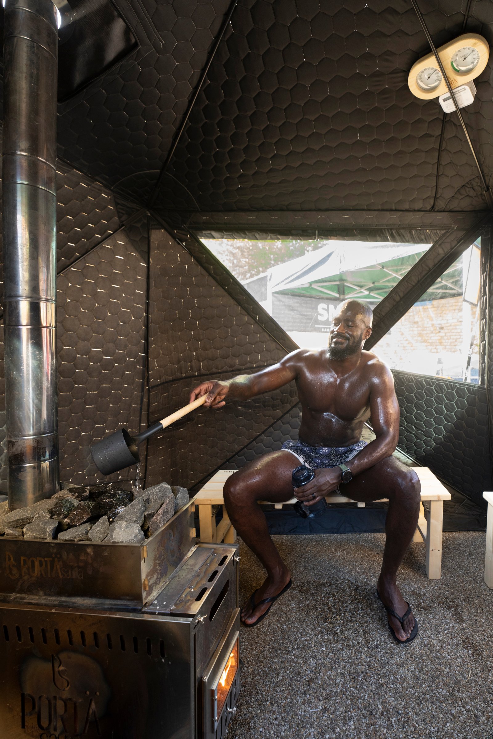 Man in the SMÜG sauna with urban skyline visible — on-location welfare